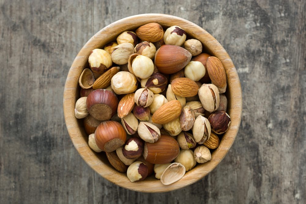 Assorted mixed nuts in bowl on wooden table