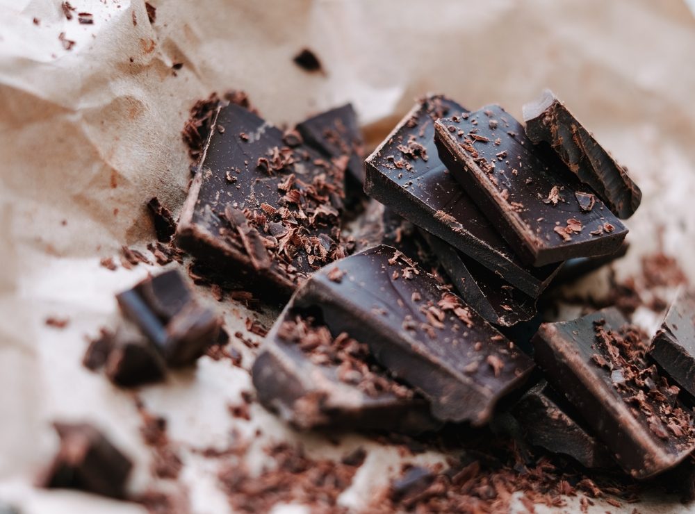 squares and shavings of dark chocolate on wax paper