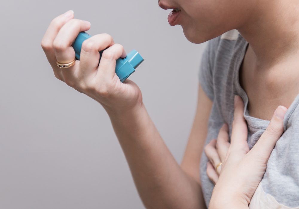 Asian woman using a pressurized cartridge inhaler extended pharynx, Bronchodilator
