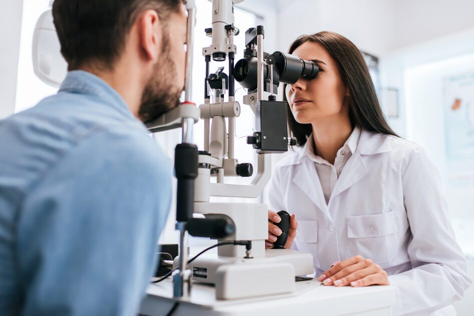 Female ophthalmologist is checking the eye vision of young man in modern clinic.