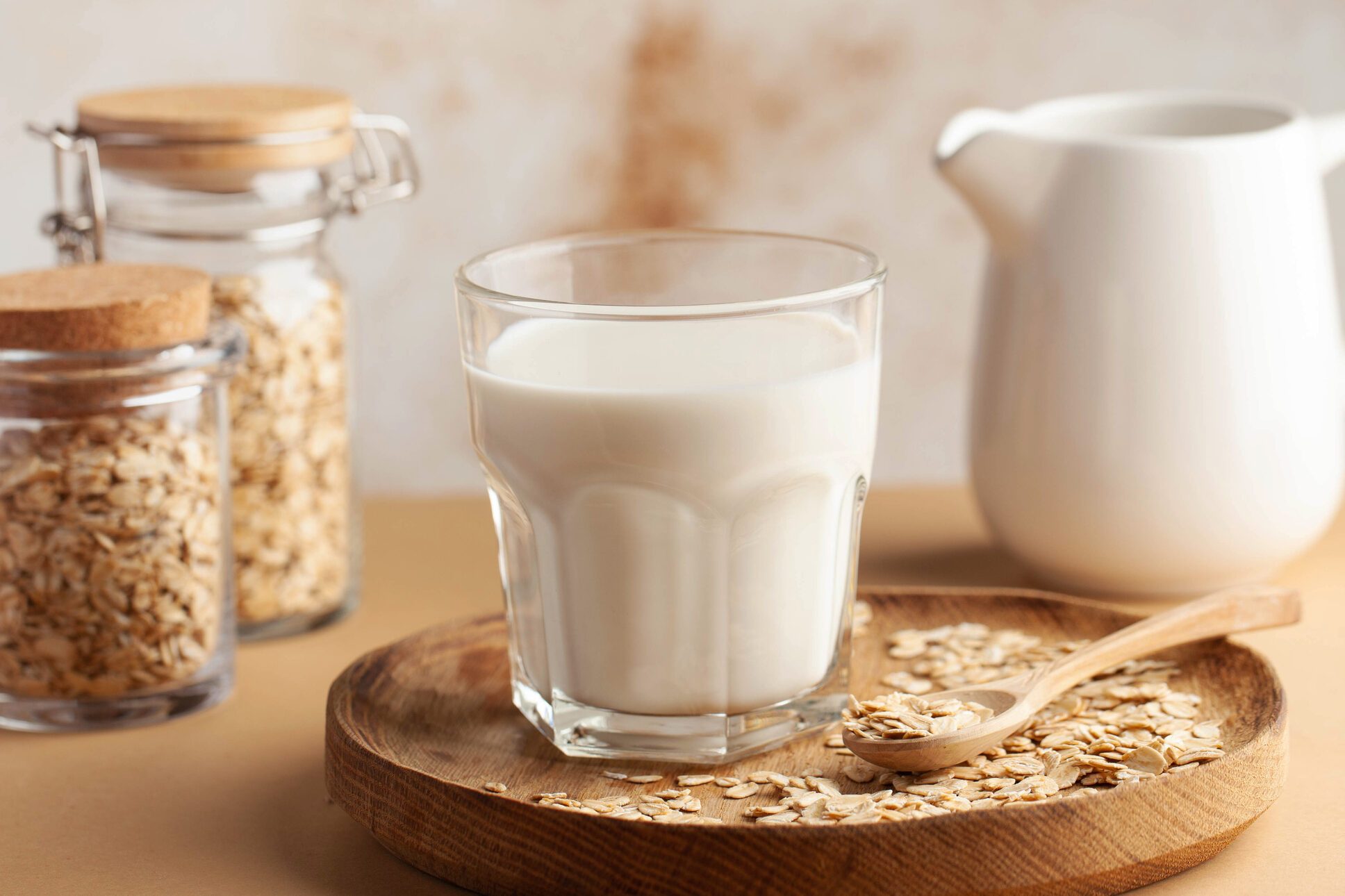 Oat milk in a glass, surrounded by jars of oats