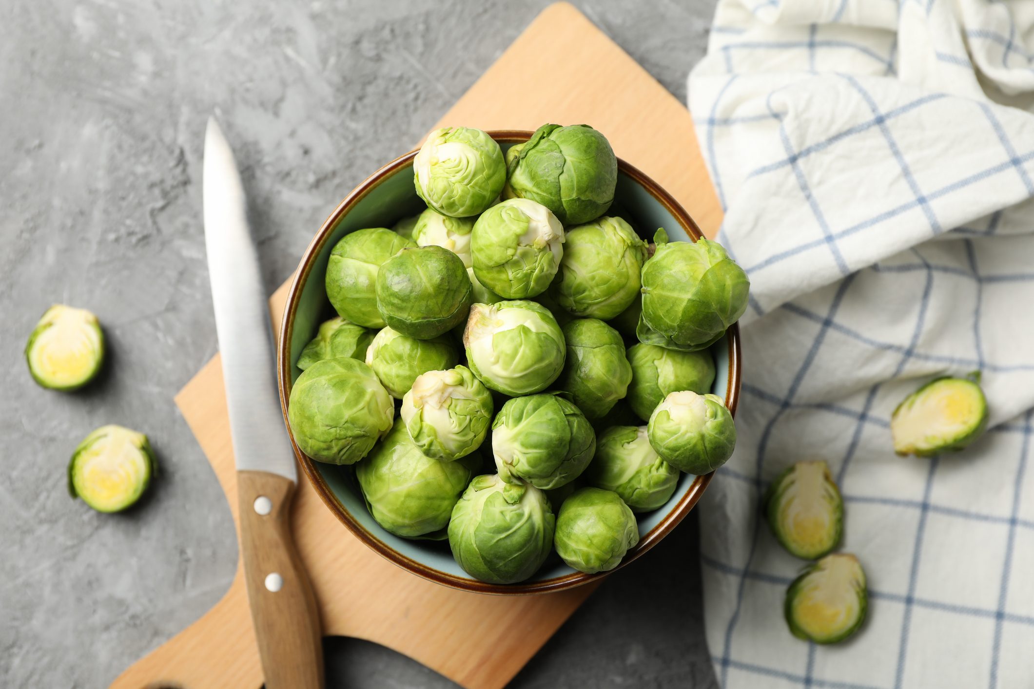 Composition with bowl of brussels sprout on grey background, top view