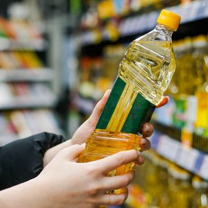 Close Up Of Hand Holding Bottle Of Sunflower Oil At Store