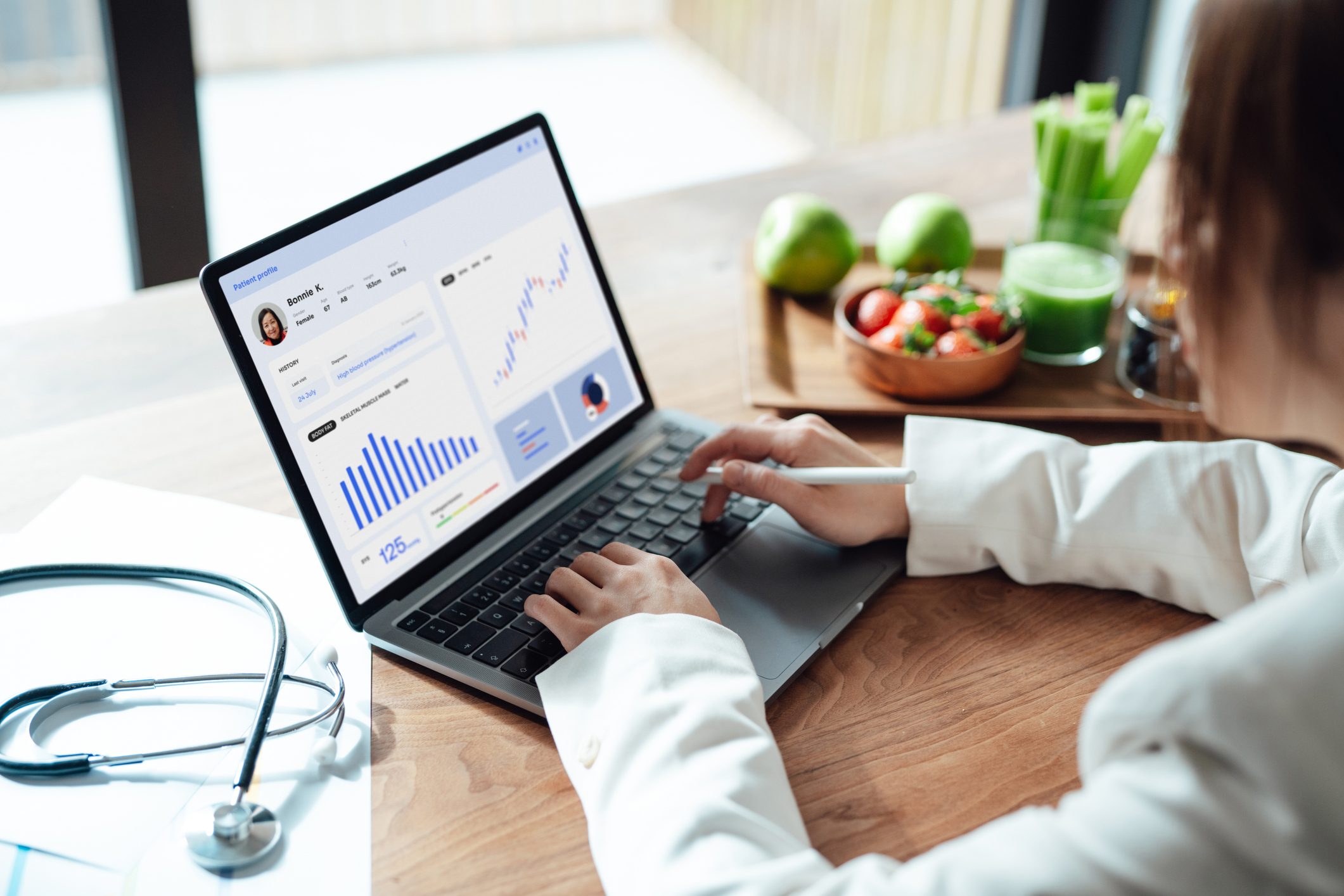 Over the shoulder view of a female medical practitioner analysing patient’s health records on laptop