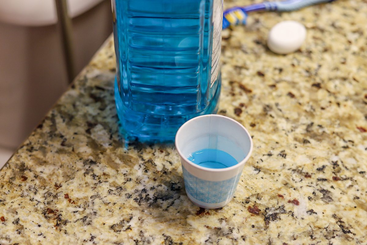 disposable paper cup with mouthwash on bathroom counter